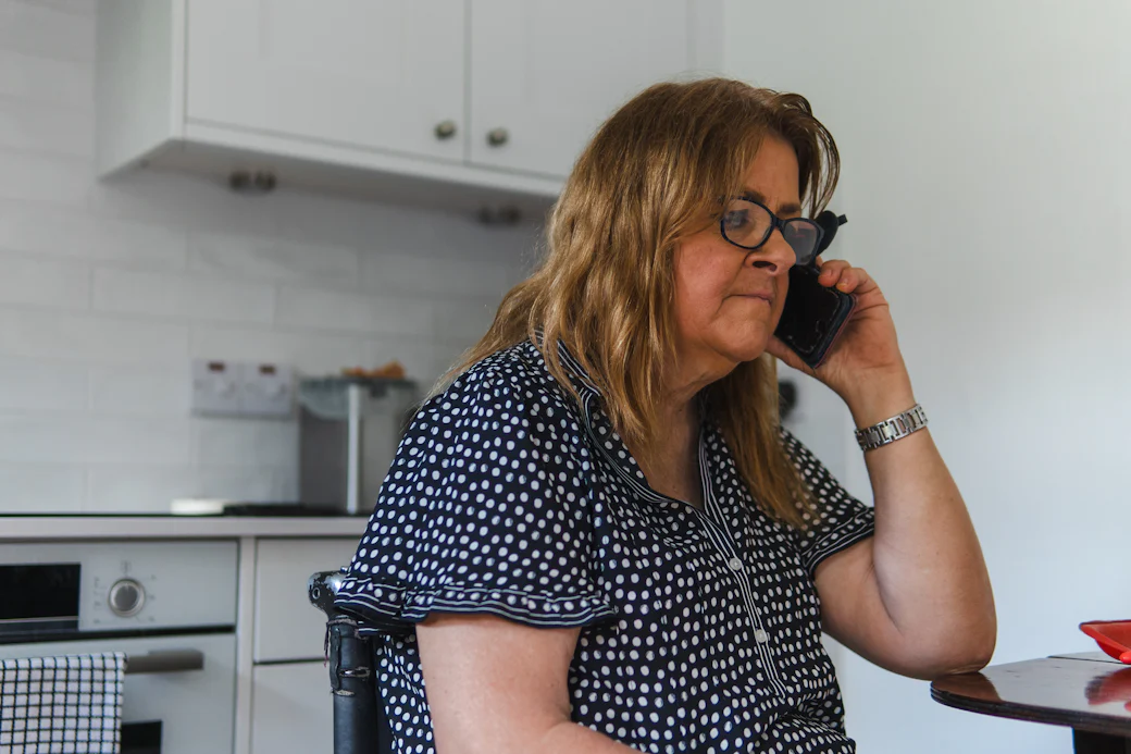 Une femme échange au téléphone depuis sa cuisine.